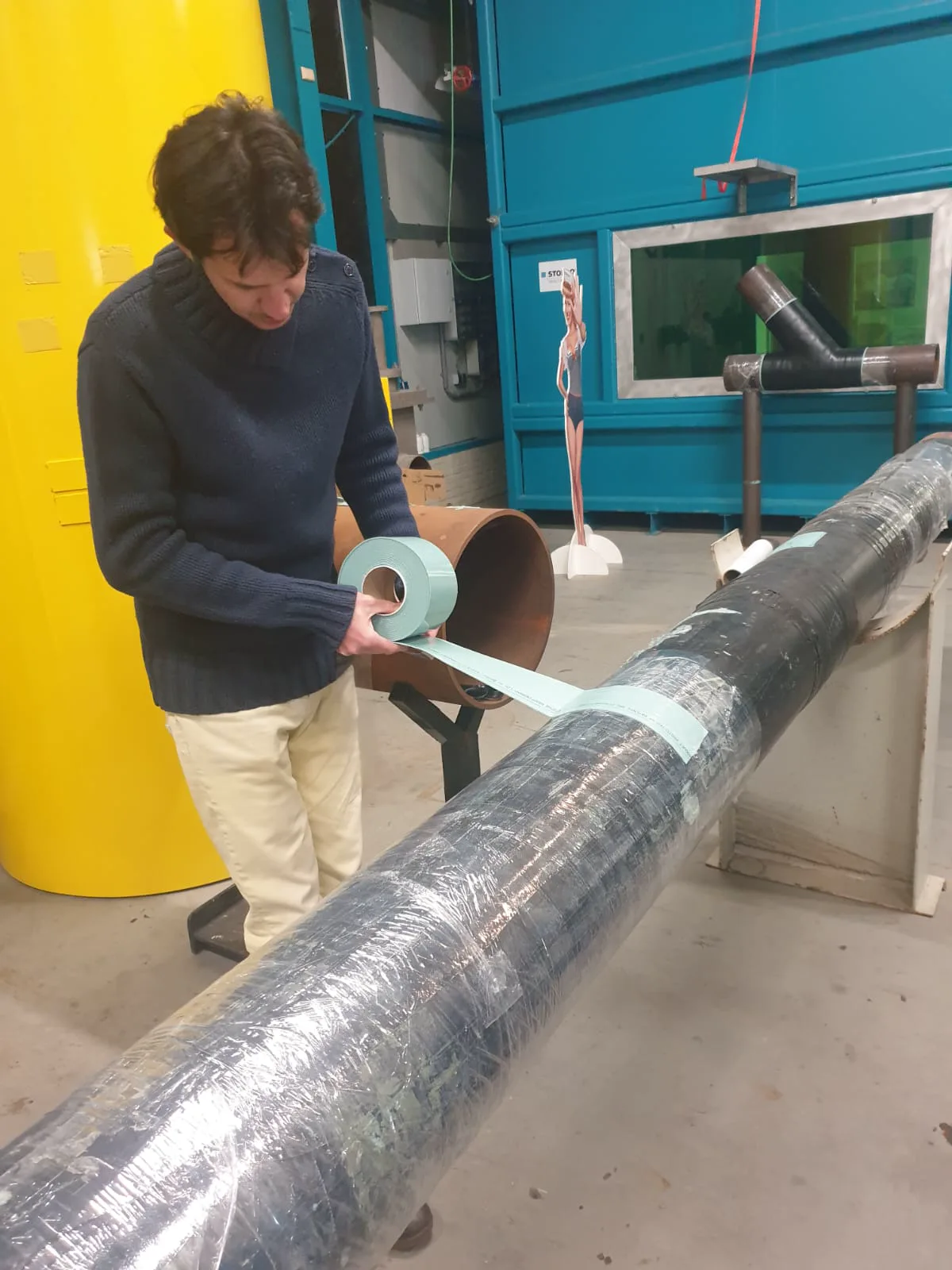 A field technician applying protective treatment to a corroded industrial vessel